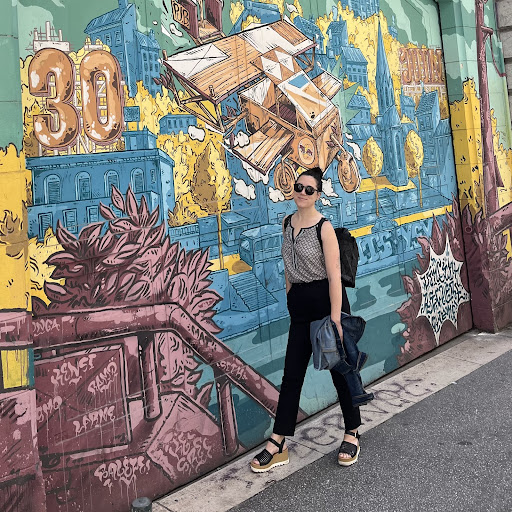 Photo of Kelsey standing in front of a mural