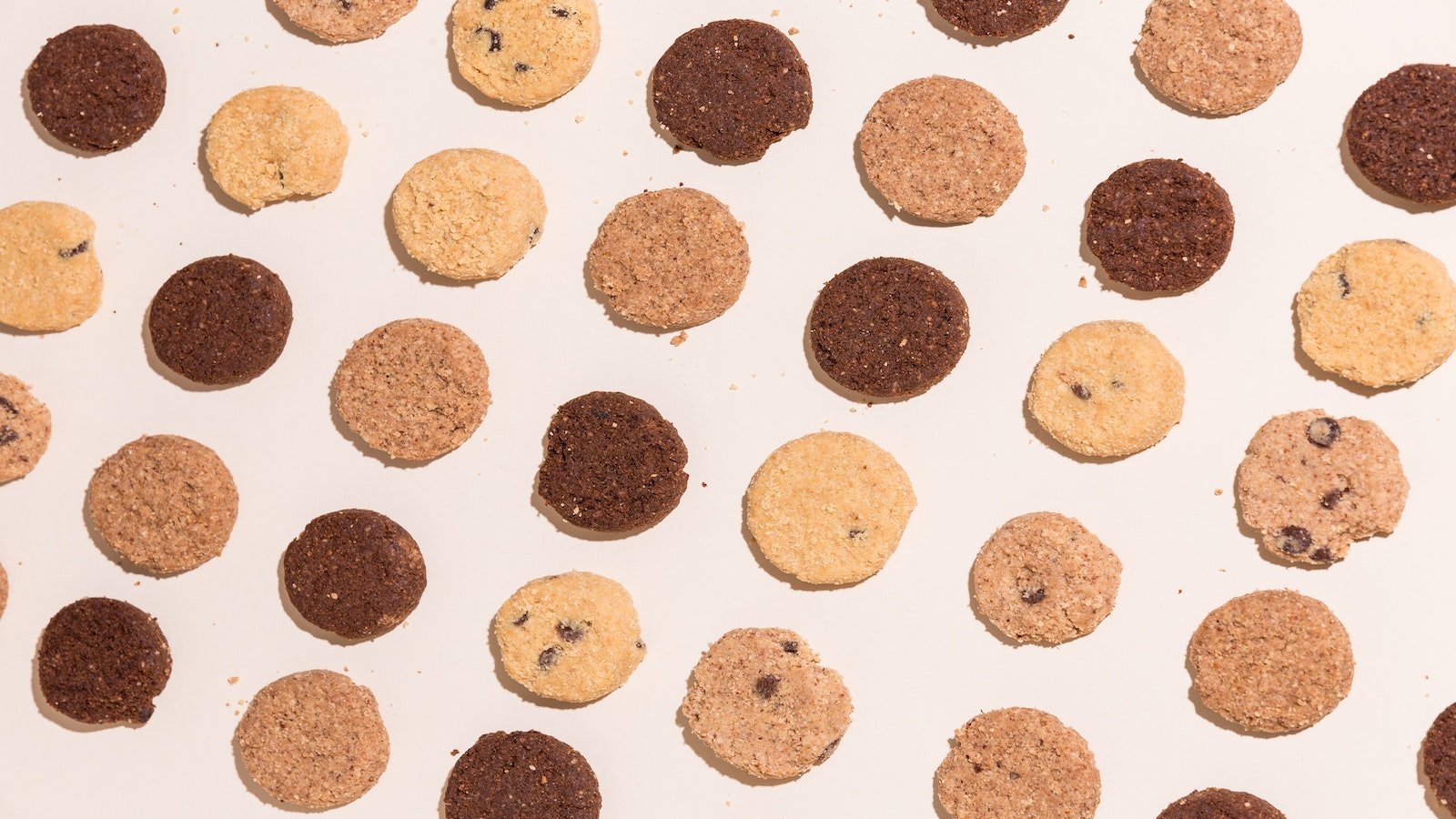 Different types of cookies evenly spread on a flat surface. 